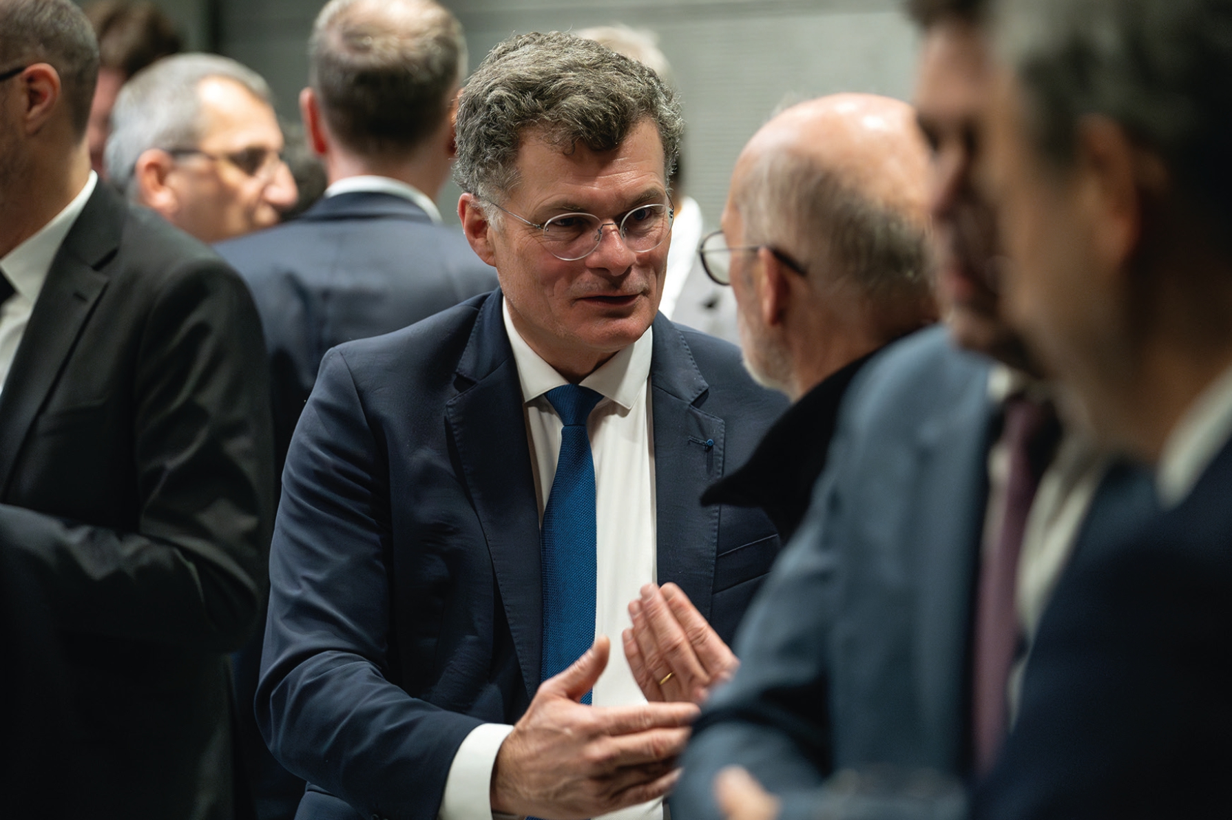Portrait de Benoît de Ruffray en costume en train de discuter au milieu d’un groupe.