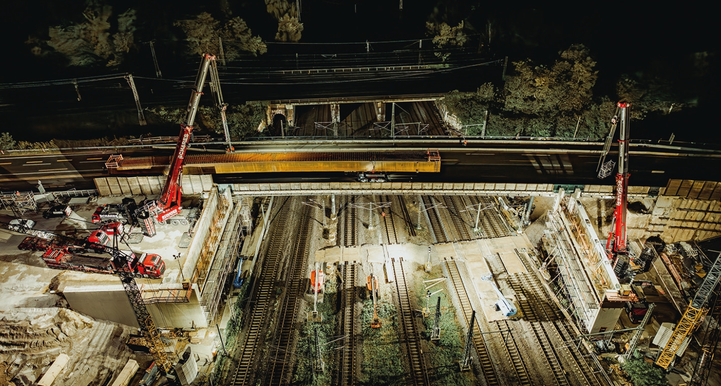 Photo de nuit d’un chantier ferroviaire. Des projecteurs puissants l’illuminent.